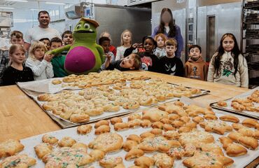 Kinder stehen mit Kruschel um einen Tisch mit fertigen Gebäcken